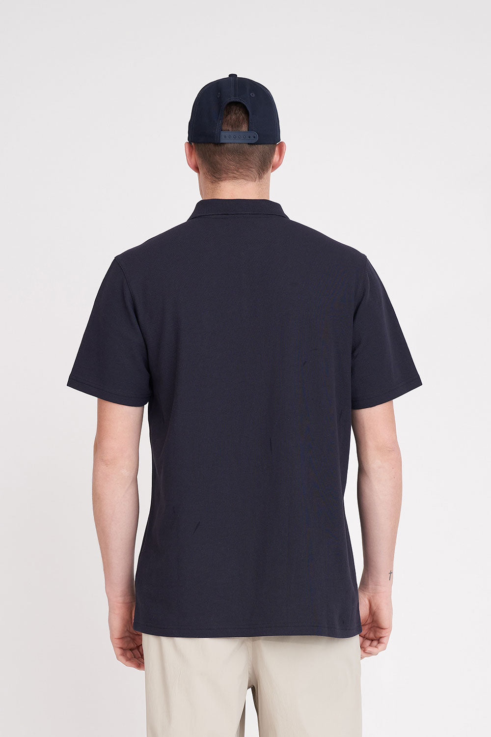 Person wearing a navy polo shirt and cap on a white background